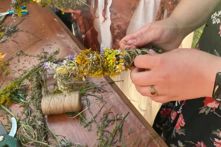 Dłonie wiążące bawełnianym sznurkiem pęczek świeżych ziół podczas przygotowywania naturalnego kadzidła DIY